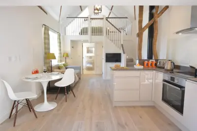 a kitchen with white cabinets and a table and chairs at Carriage House, Bruisyard in Framlingham