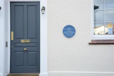 a blue door on a white building with a window at Skimming Stones, Aldeburgh in Aldeburgh