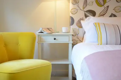 a bedroom with a yellow chair next to a bed at Skimming Stones, Aldeburgh in Aldeburgh