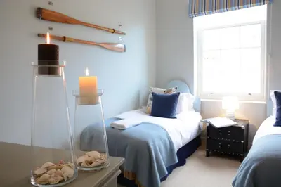a bedroom with two beds and a table with a candle at Skimming Stones, Aldeburgh in Aldeburgh