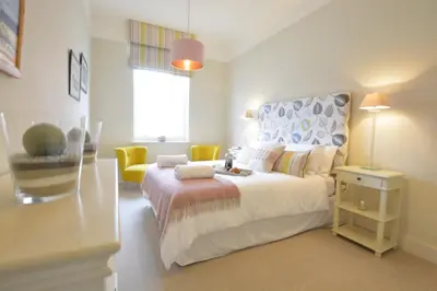 a bedroom with a large white bed and yellow chairs at Skimming Stones, Aldeburgh in Aldeburgh