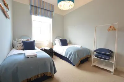 a bedroom with two beds and a mirror at Skimming Stones, Aldeburgh in Aldeburgh
