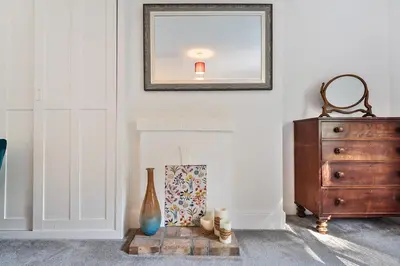 a room with a fireplace with a mirror and a dresser at Bedingfield House, nr Debenham in Debenham