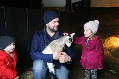 a man and two children holding a baby goat at The Round House in Kettleburgh