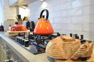 an orange tea kettle sitting on top of a stove at 53 Tern Cottage, Aldeburgh in Aldeburgh