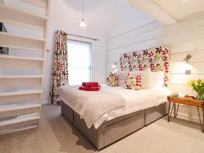 a bedroom with a bed with a red hat on it at 51 Tern Cottage, Aldeburgh in Aldeburgh