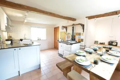 a kitchen with white cabinets and a table with plates on it at The White House with Studio in Homersfield
