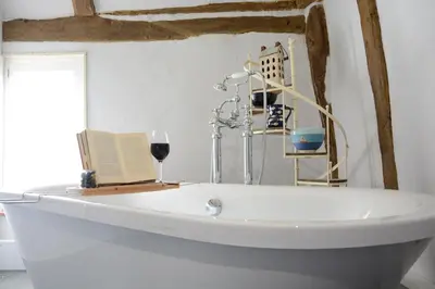 a white bath tub with a book and a glass of wine at The White House with Studio in Homersfield