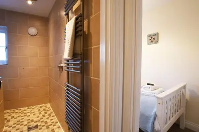 a bathroom with a shower and a bed in a room at Smugglers Rest, Aldeburgh in Aldeburgh