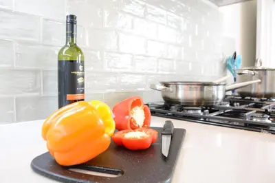 a bottle of wine and some tomatoes on a cutting board at Wide Skies, Aldeburgh in Aldeburgh