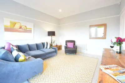 a living room with a blue couch and a chair at Wide Skies, Aldeburgh in Aldeburgh