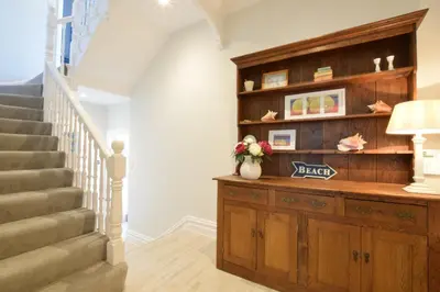 a hallway with a staircase with a wooden cabinet and a stair case at Wide Skies, Aldeburgh in Aldeburgh