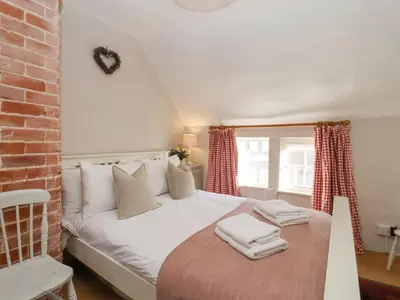 a bedroom with a white bed with towels on it at Rosemary Cottage, Aldeburgh in Aldeburgh