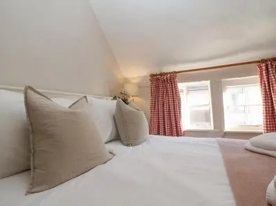 a bedroom with a white bed and two windows at Rosemary Cottage, Aldeburgh in Aldeburgh