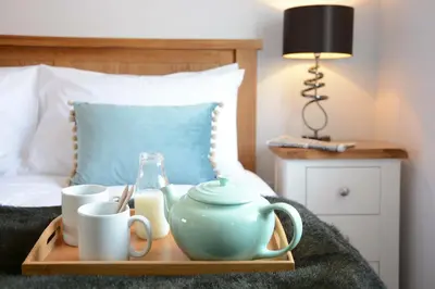 a tray with a teapot and cups on a bed at Lapwings, Aldeburgh in Aldeburgh