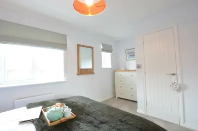 a bedroom with a bed and a dresser and a window at Lapwings, Aldeburgh in Aldeburgh