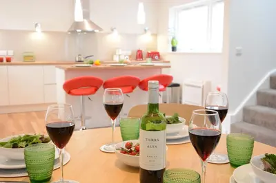 a table with glasses of wine and a plate of food at Bramertons Nest, Long Melford in Long Melford