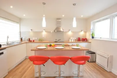 a kitchen with a large island with red bar stools at Bramertons Nest, Long Melford in Long Melford