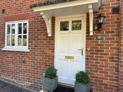 a white door on a brick house with two plants at Bluebelle Cottage, Peasenhall in Peasenhall