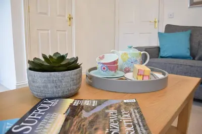 a coffee table with a book and a plate of food at Bluebelle Cottage, Peasenhall in Peasenhall