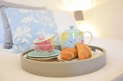 a tray with croissants and a teapot and cups on a bed at Bluebelle Cottage, Peasenhall in Peasenhall