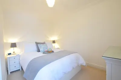 a white bedroom with a white bed and a desk at Bluebelle Cottage, Peasenhall in Peasenhall