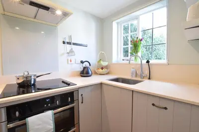 a kitchen with white cabinets and a sink and a window at Satis Cottage, Westleton in Westleton