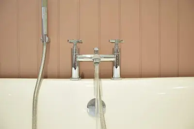 a bath tub with two faucets and a sink at Satis Cottage, Westleton in Westleton