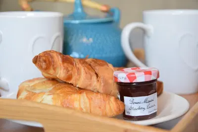 a plate with two croissants and a jar of jam at Satis Cottage, Westleton in Westleton