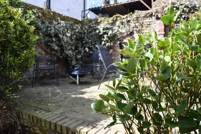 a patio with a chair and a bench in a garden at Satis Cottage, Westleton in Westleton