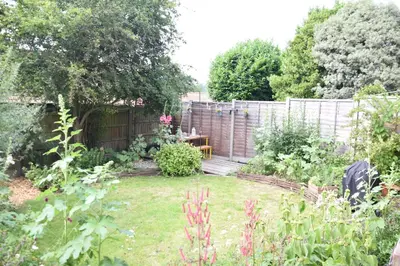 a garden with a wooden deck and a fence at Rosedene, Rickinghall in Rickinghall