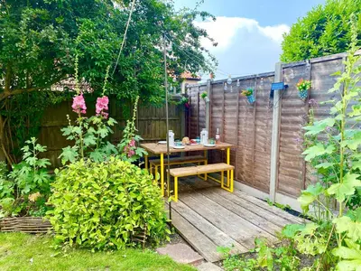 a wooden deck with a table in a garden at Rosedene, Rickinghall in Rickinghall