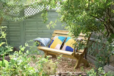 a wooden bench sitting in a garden at Rosedene, Rickinghall in Rickinghall