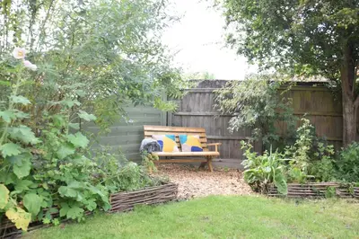 a wooden bench sitting in a garden next to a fence at Rosedene, Rickinghall in Rickinghall