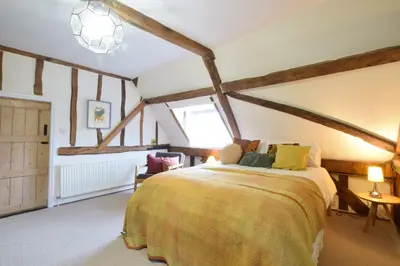 a bedroom with a bed in a room with beams at Church Farmhouse, Cookley in Halesworth