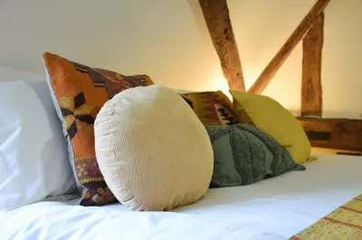 a pile of pillows sitting on top of a bed at Church Farmhouse, Cookley in Halesworth