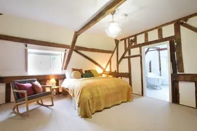 a bedroom with a bed and a chair in a room at Church Farmhouse, Cookley in Halesworth