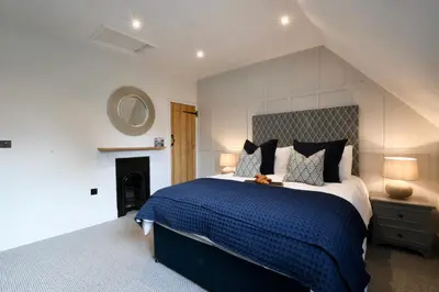 a bedroom with a large bed with a blue comforter at Arlo Cottage, Orford in Orford