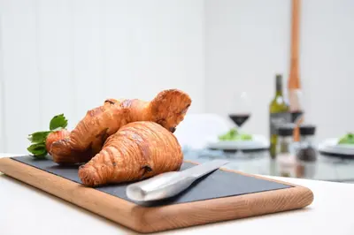 a loaf of bread on a cutting board with a knife at Arlo Cottage, Orford in Orford