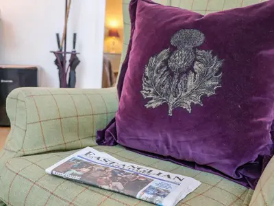 a purple pillow and a magazine on a couch at The Bothy at Snape Hall in Snape