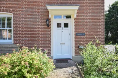 a white door on a brick house with bushes at The Gallery, Blythburgh in Blythburgh