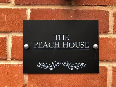a sign on a brick wall with the peach house at Peach House, Aldeburgh in Aldeburgh