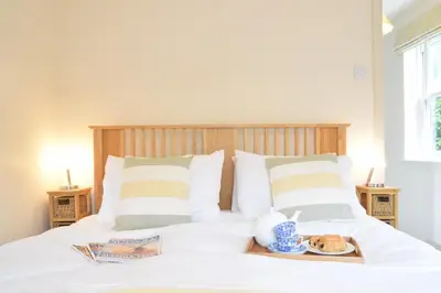 a white bed with a tray of food on it at Peach House, Aldeburgh in Aldeburgh