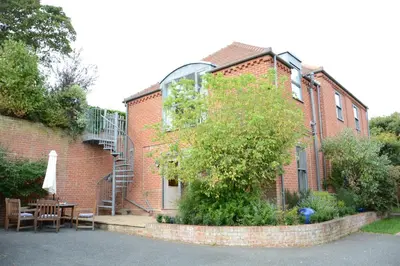 a brick building with a table and a tree in front of it at Peach House, Aldeburgh in Aldeburgh