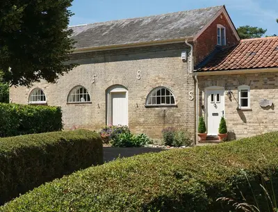 an old brick house with a white door at Stable Cottage at the Grove, Great Glemham in Framlingham