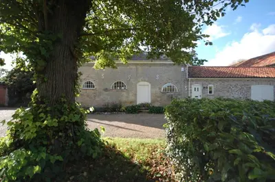 a large tree in front of a stone building at Stable Cottage at the Grove, Great Glemham in Framlingham
