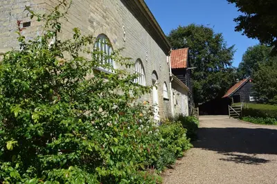a brick building with a bush in front of it at Stable Cottage at the Grove, Great Glemham in Framlingham