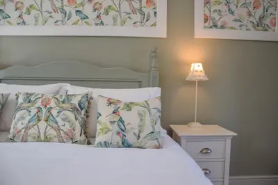 a bed with pillows and a lamp on a night stand at 1 Coconut Cottage, Long Melford in Long Melford