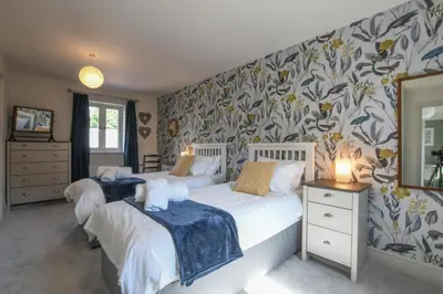 two beds in a bedroom with floral wallpaper at 1 Coconut Cottage, Long Melford in Long Melford