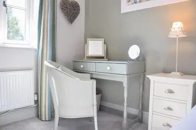 a bedroom with a dresser and a mirror and a chair at 1 Coconut Cottage, Long Melford in Long Melford